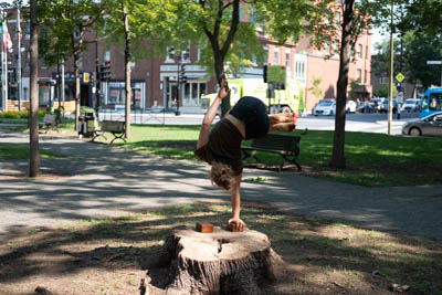 Artiste de cirque faisant un équilibre groupé à une main sur un bloc.